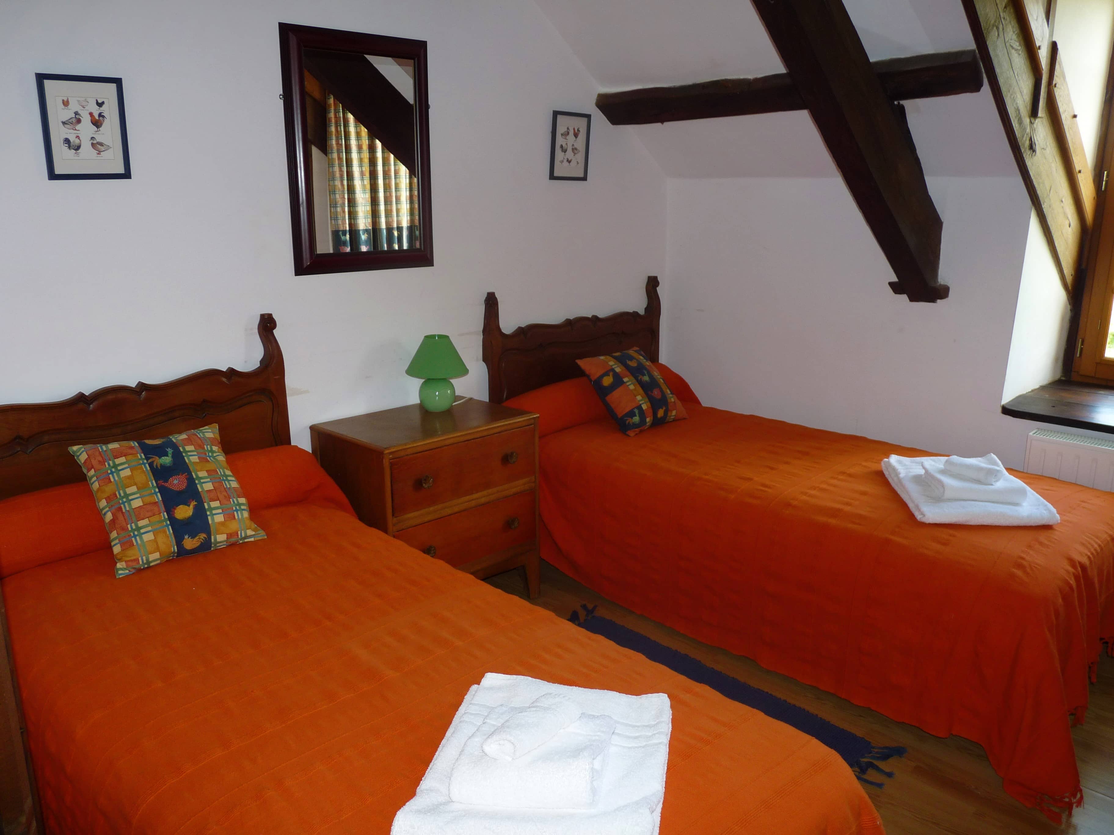Spacious and comfortable bedroom of La Julerie cottage in Brittany, France, with a king-size bed, elegant rustic decor, a stone fireplace, and a panoramic view of the surrounding countryside. Perfect for a peaceful night's sleep after a day of sightseeing in the Brittany region.